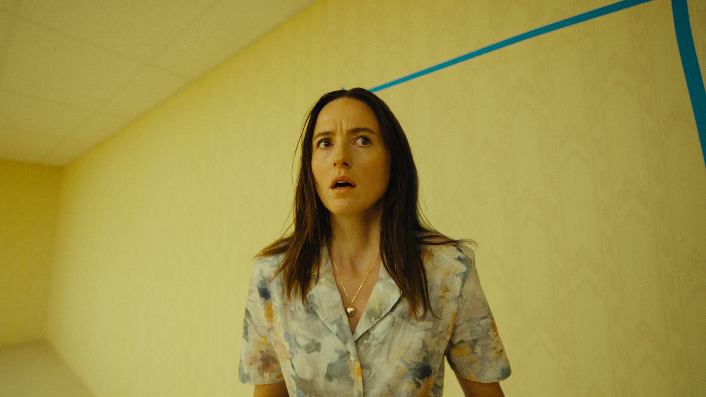 A woman stands in a yellow-lit room in an official image for A24's Backrooms
