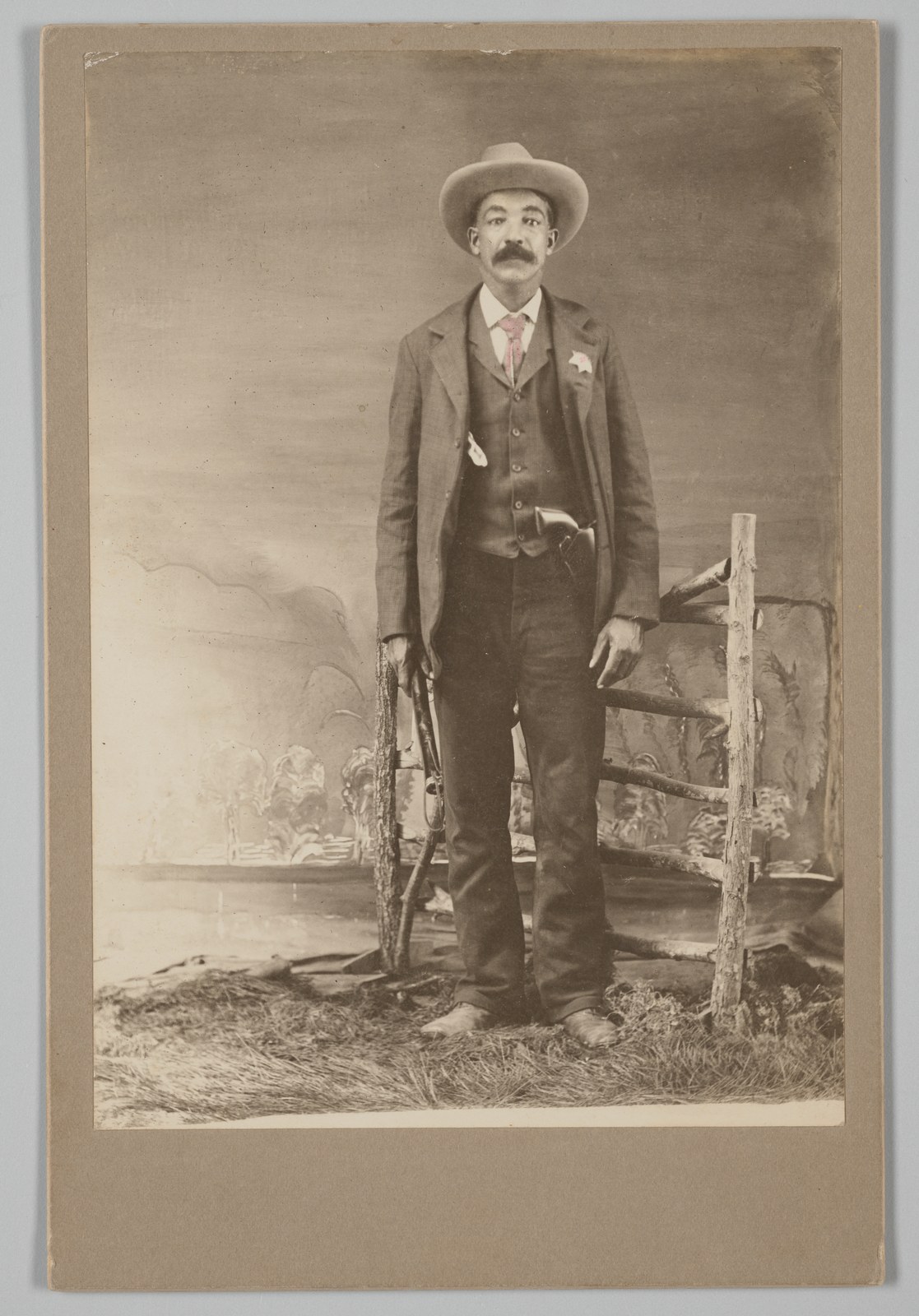 Bass Reeves standing in a studio portrait around 1902, wearing a hat, badge and holstered revolver