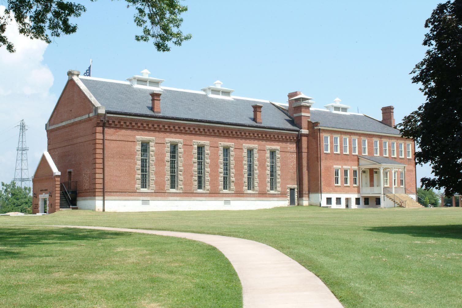 The red-brick historic barracks, courthouse and jail building at Fort Smith National Historic Site, with a path and lawn in front