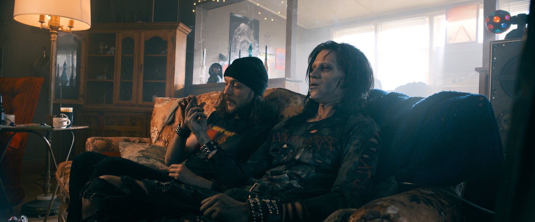 Two metalheads sit on a couch in an official Deathgasm II: Goremageddon film still