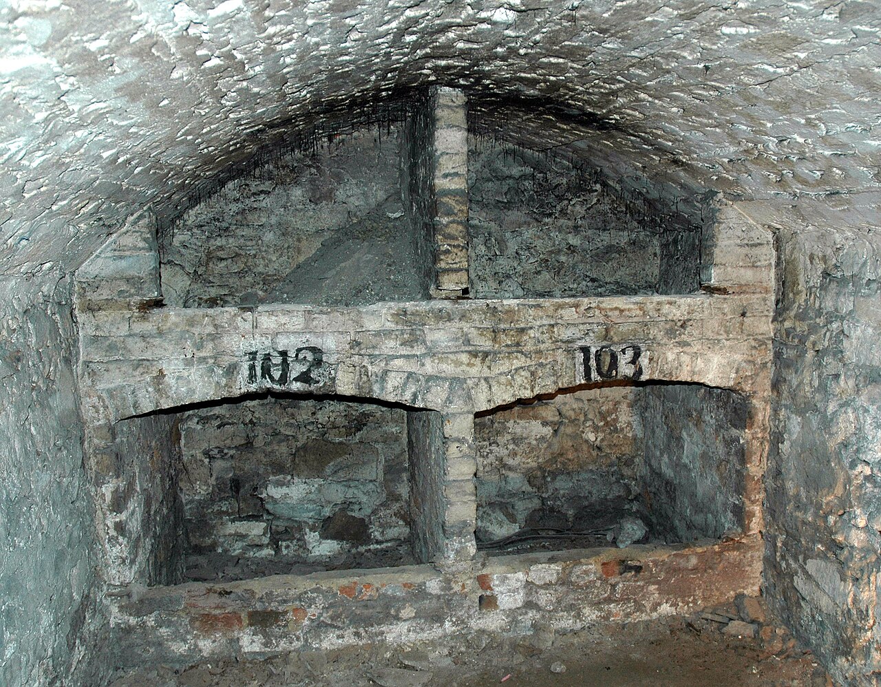 Interior of a South Bridge vault chamber in Edinburgh, showing stone arches and numbered storage bays marked 102 and 103