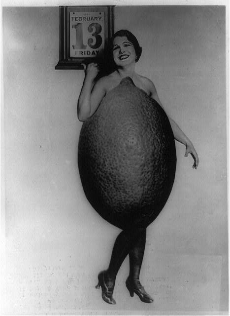 Rose Cade in a lemon costume pointing to a calendar marked Friday February 13 in a 1920 publicity photograph