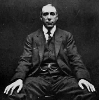 Black-and-white seated portrait of psychical researcher Harry Price