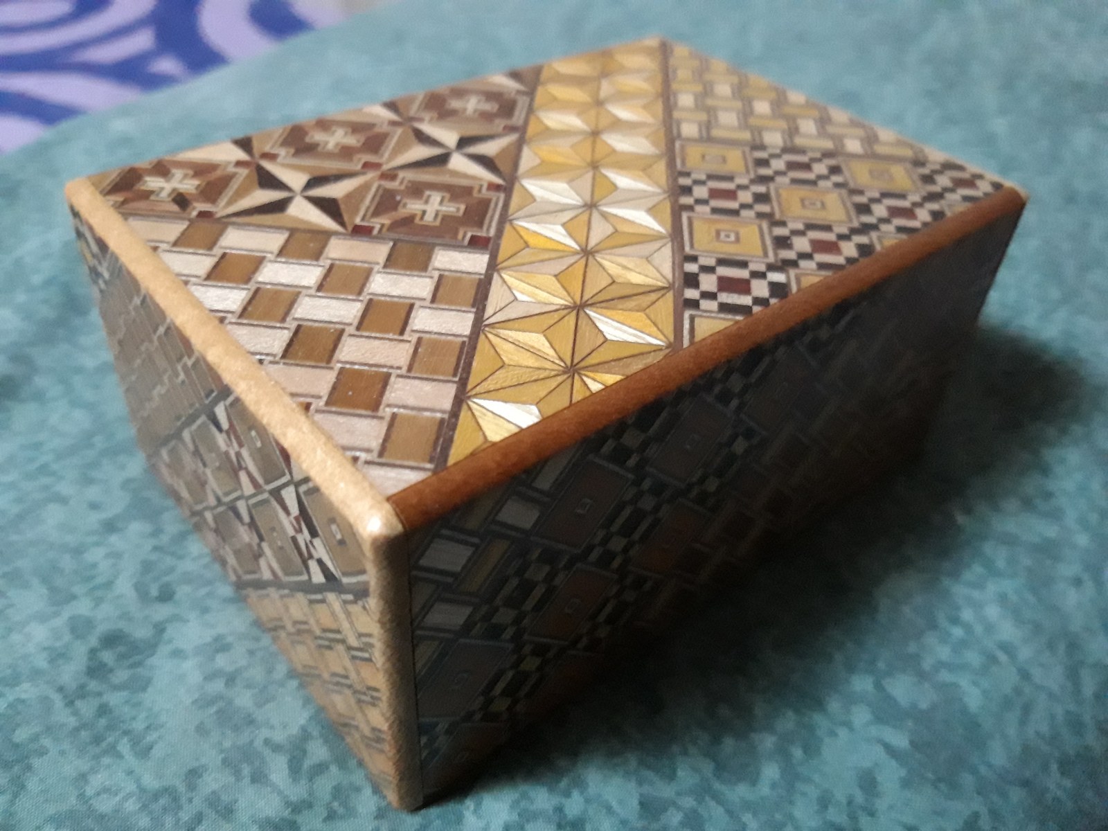 A real Japanese yosegi puzzle box in its closed configuration; mechanical puzzle context, not a Hellraiser prop or occult object