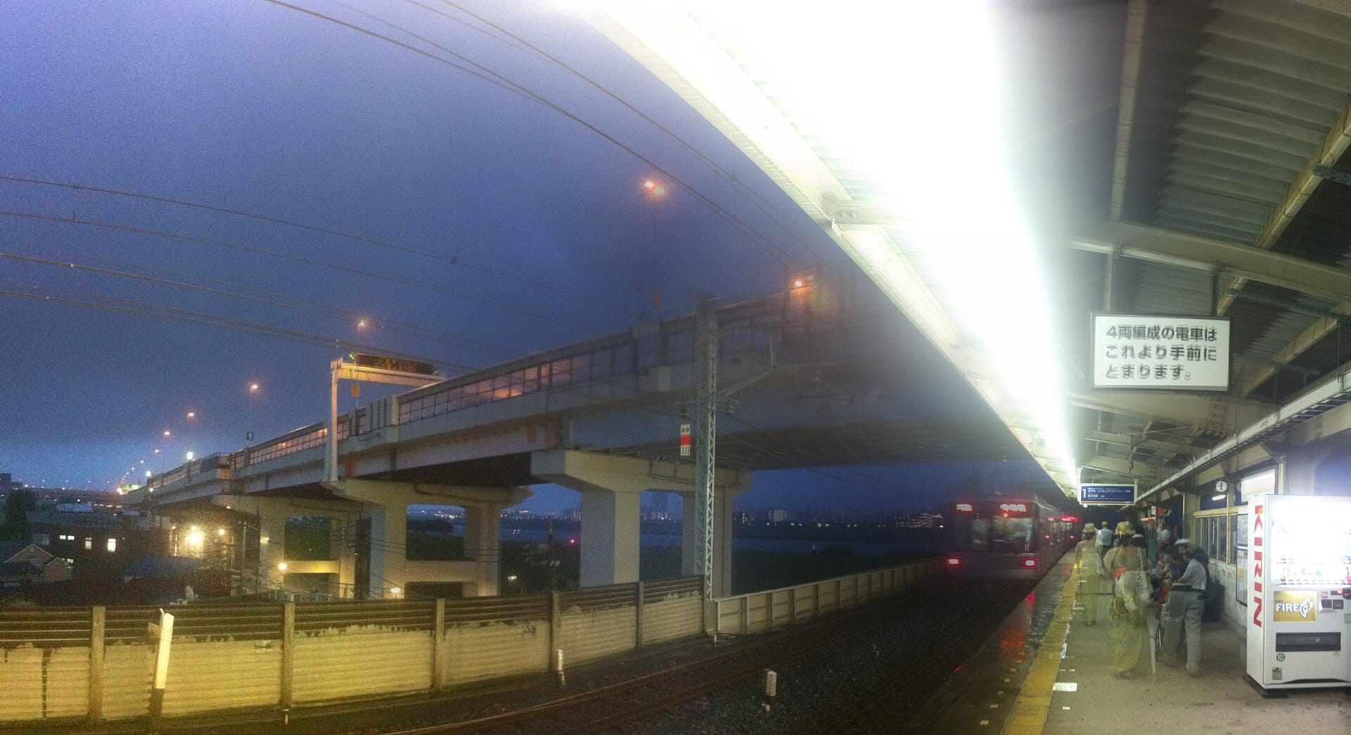 A rain-soaked Japanese train station platform at night