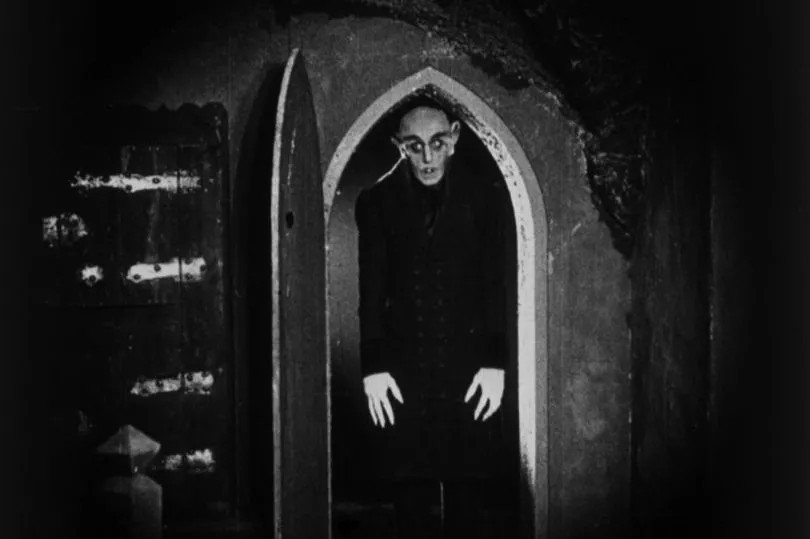 Count Orlok stooping through an arched doorway, from Nosferatu (1922)