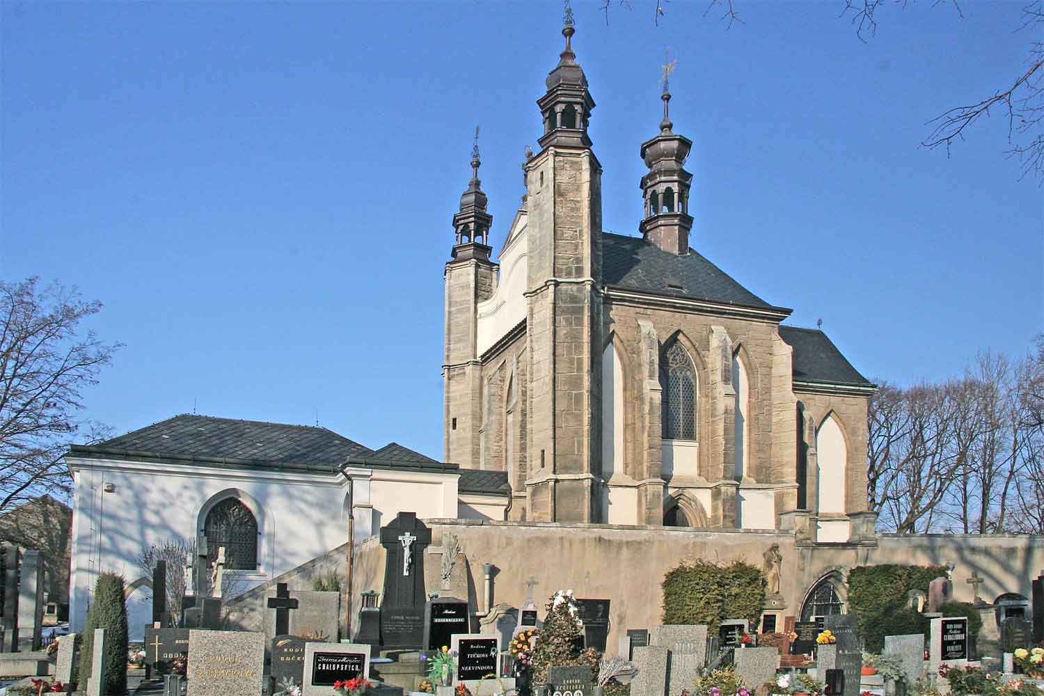Exterior of the Cemetery Church of All Saints at Sedlec, a two-storey Gothic building surrounded by a modern cemetery
