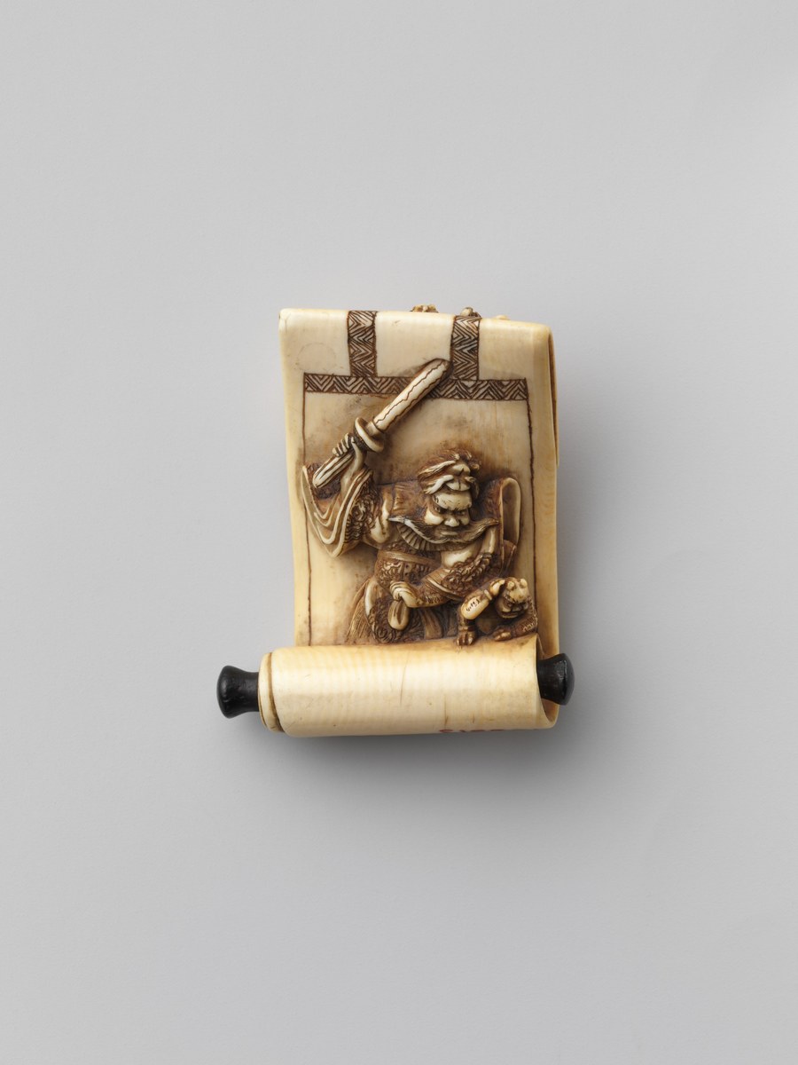 Japanese ivory netsuke carved as a scroll showing Shoki raising his sword over a cowering oni